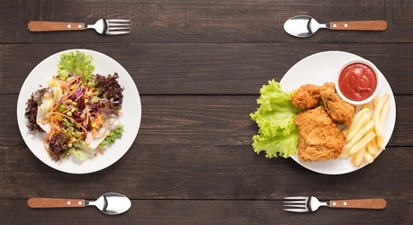 Ein Teller mit Salat steht einem Teller mit Schnitzel und Pommes gegenüber